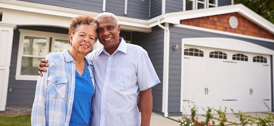 senior couple in front of house