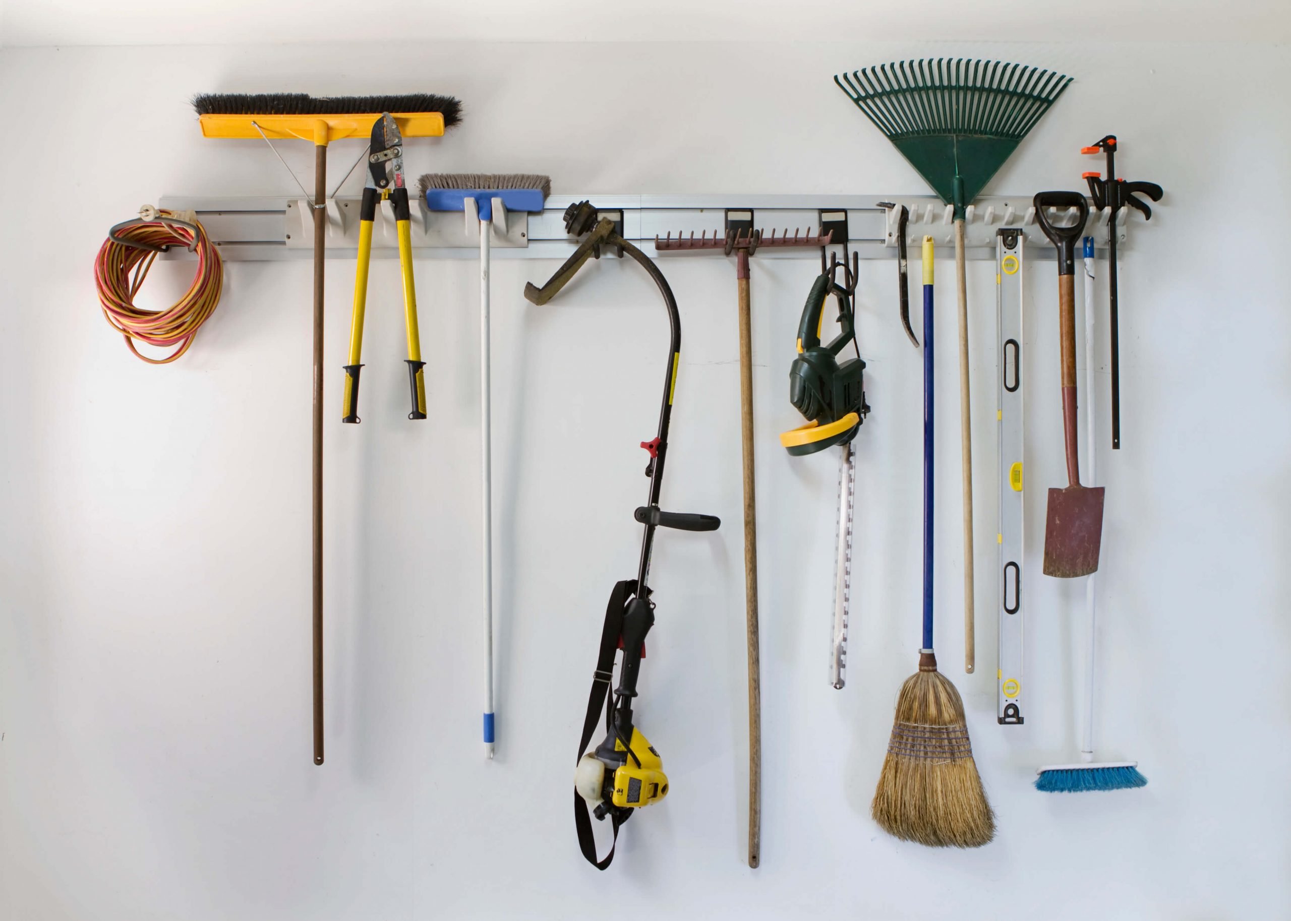 gardening and cleaning tools hanging on tool tower rack on garage wall