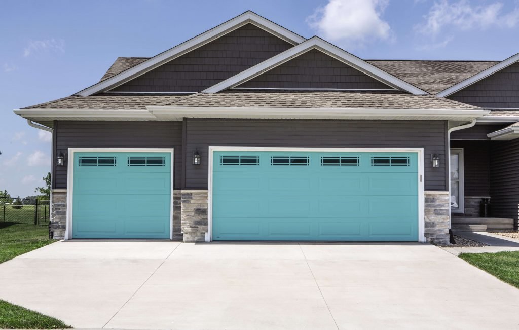 front of home with two teal garage doors